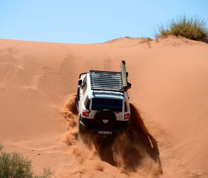A 4x4 climbing the slip face of a red dune